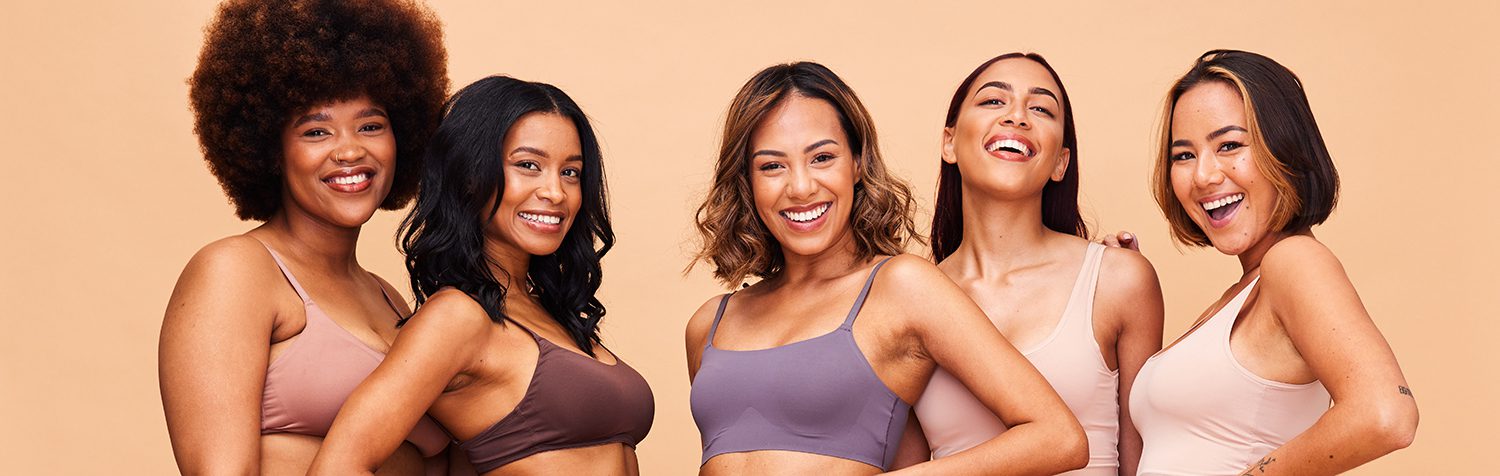 Group of diverse women smiling and embracing in a body positivity campaign.