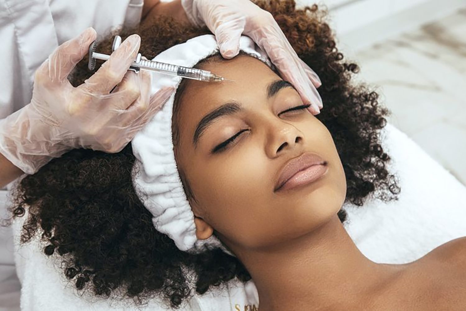 Young woman receiving a facial treatment injection at Michele Aesthetics.